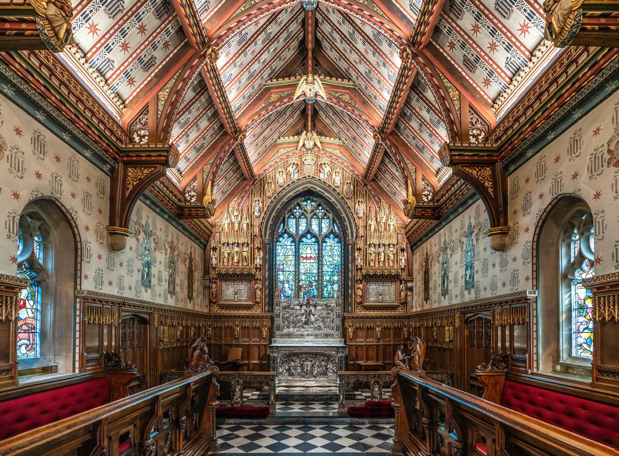 An interior image of a highly decorative church chancel featuring wood carvings and ornate silver