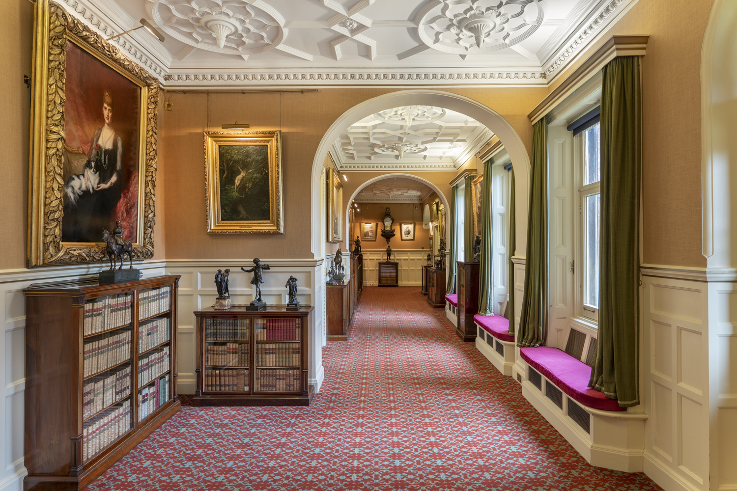 Looking down the ballroom corridor with portraits and sculptures of the British Monarch