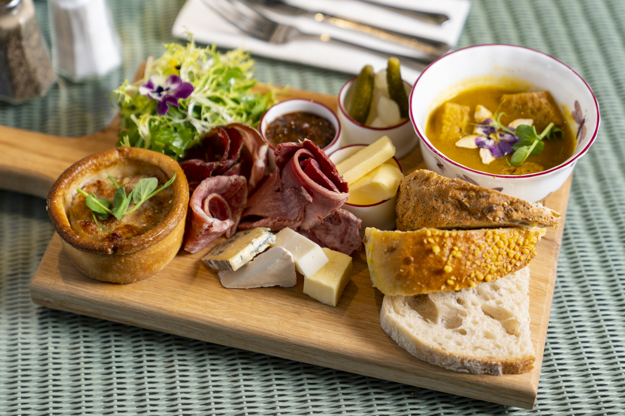 Pork pie, hams, cheese and chutneys with salad on a board showing Norfolk produce