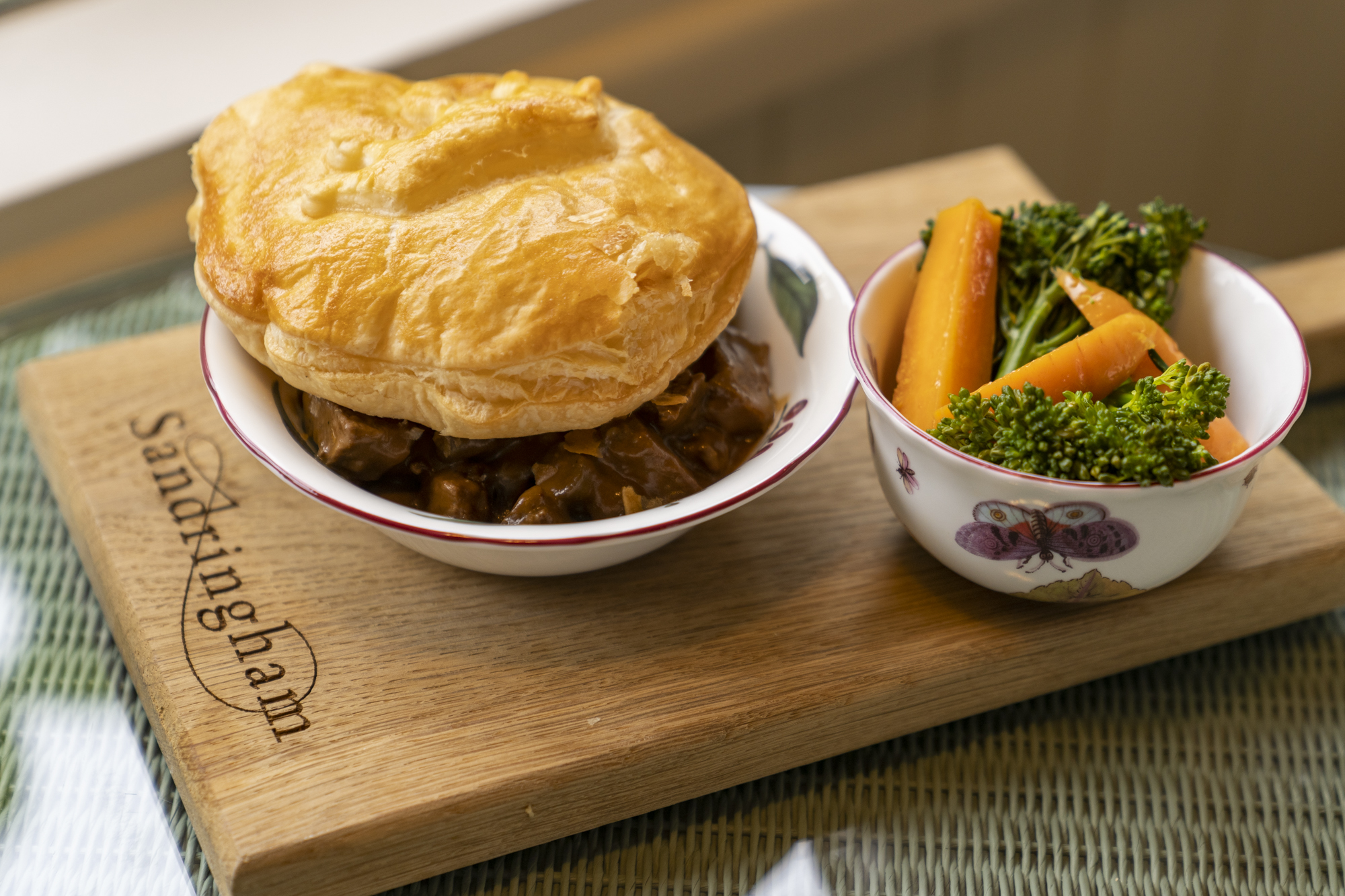 A steak pie with pastry top and vegetables